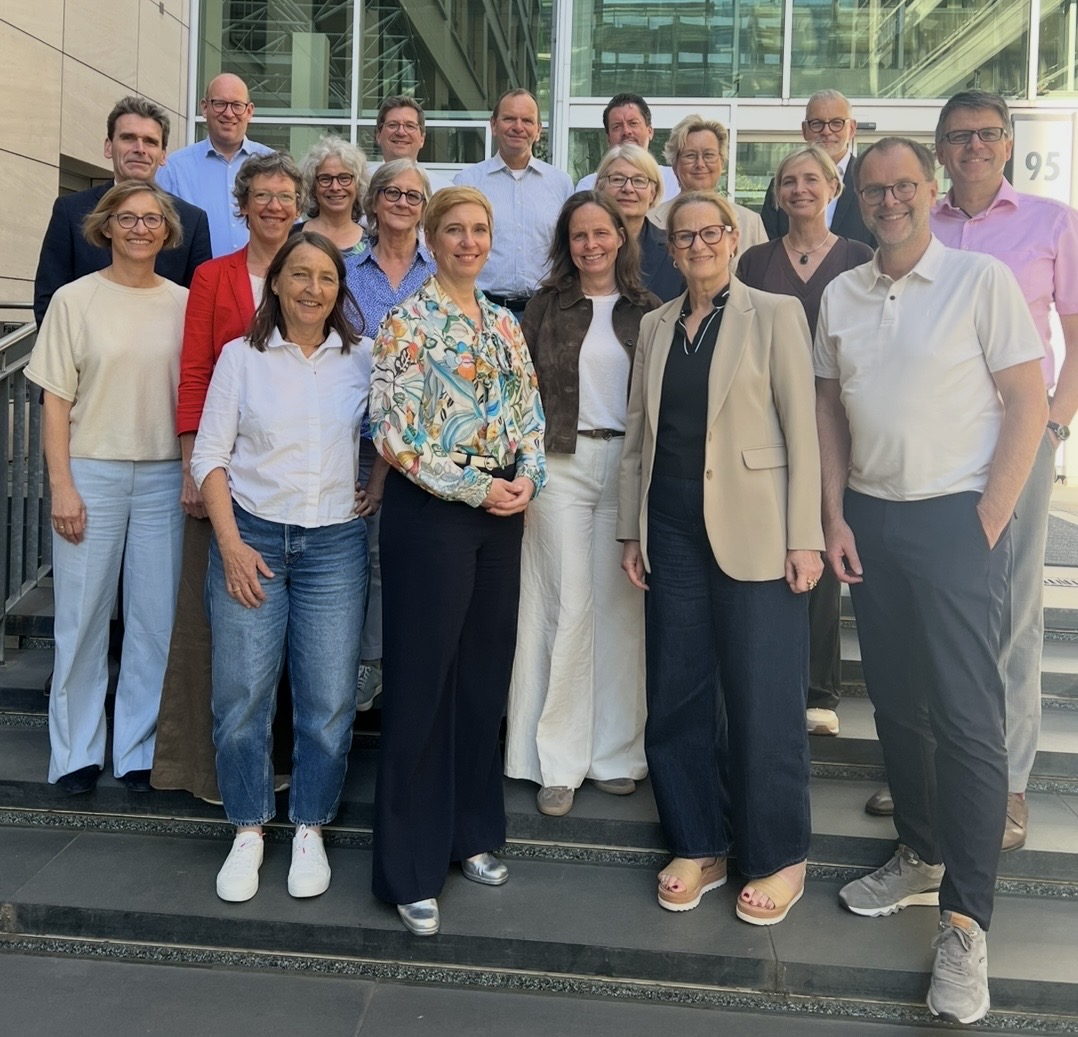 Auf dem Foto sieht man 19 Personen, die sich auf einer Treppe aufstellen.